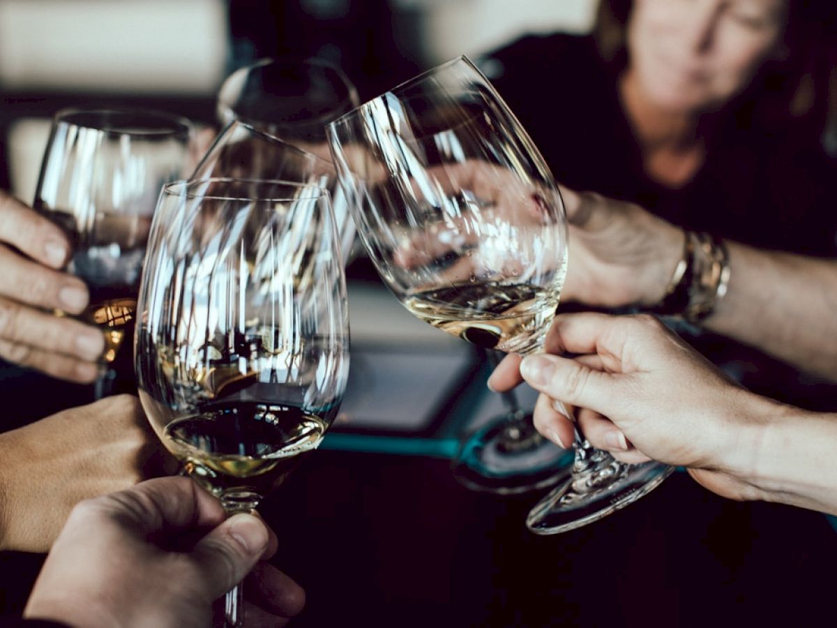 A group of people toasts with glasses of white wine, creating a celebratory atmosphere.