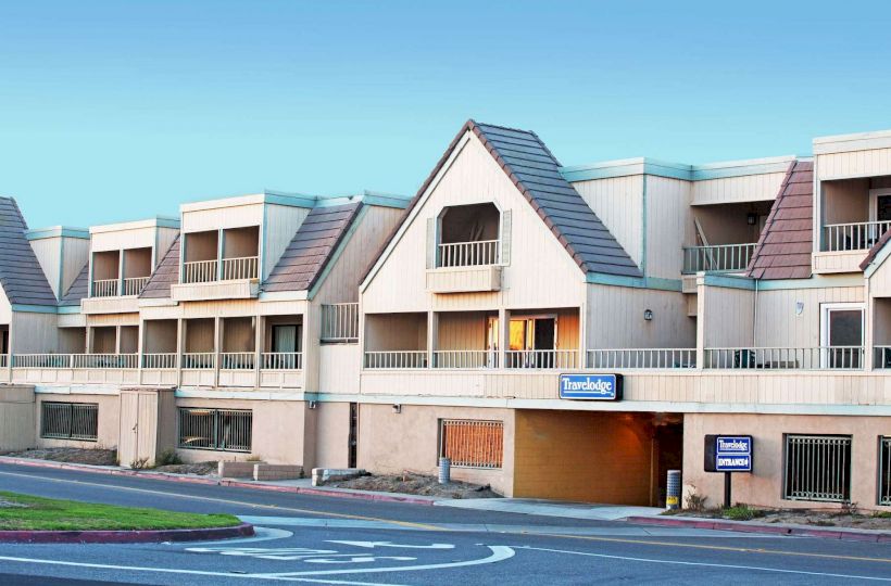 The image shows a two-story, beige colored building with brown roofs, labeled 